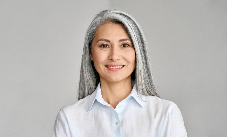 Headshot of mature 50-year old Asian business woman on grey background.